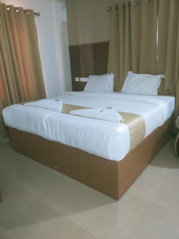 a large bed with white sheets and pillows on it at Nova Saara Palace in Kannur