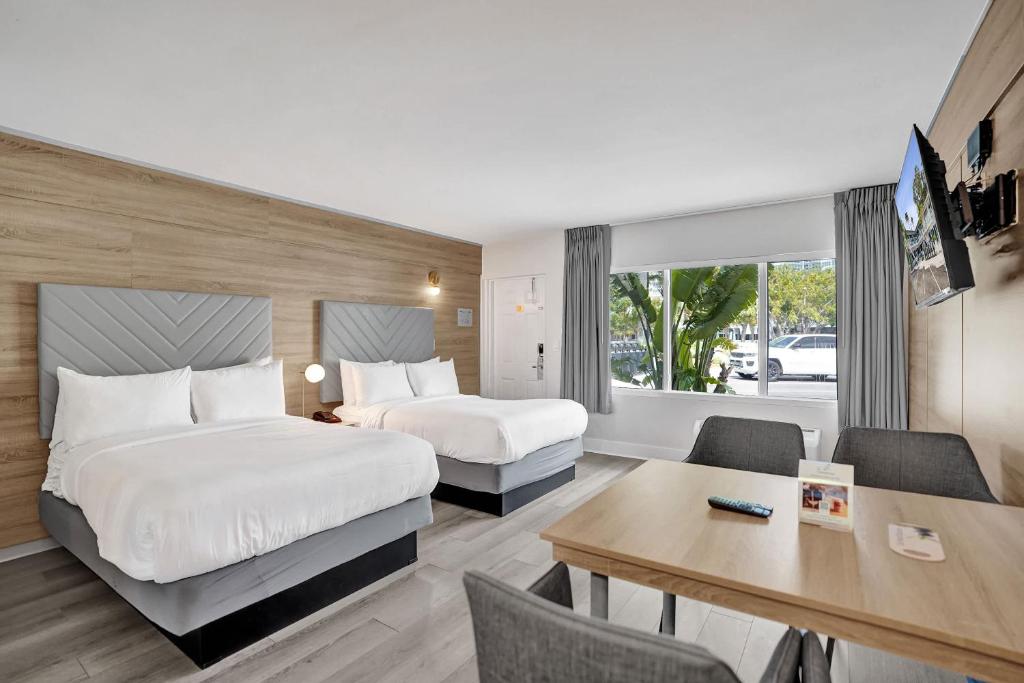 a hotel room with two beds and a desk at Ocean Blvd Two Doubles Suite with Kitchenette in Fort Lauderdale