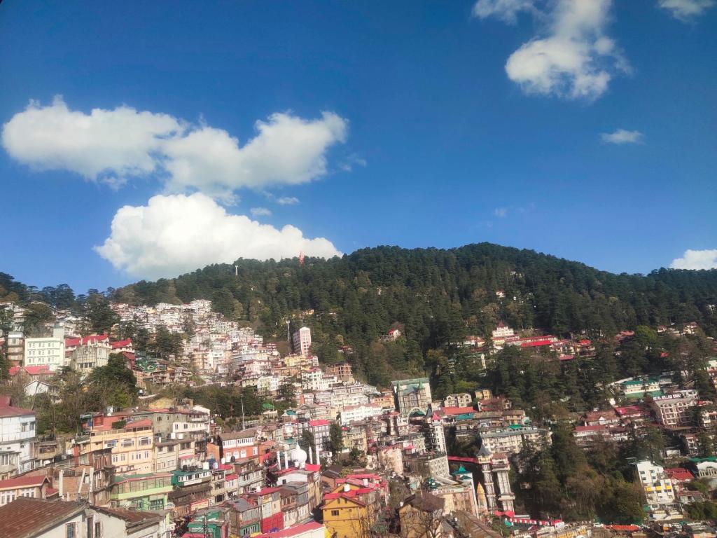 a view of a city with buildings on a hill at HideOut The Mall in Shimla