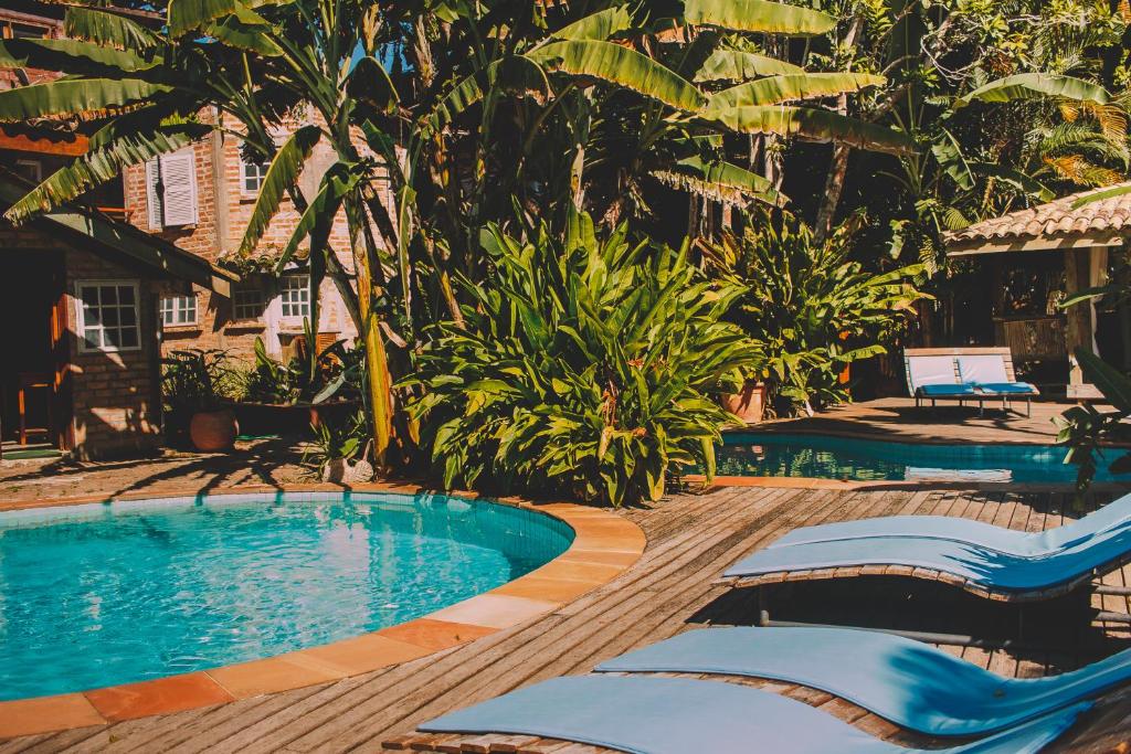 a swimming pool with two lounge chairs next to a house at Alua Camburi in Camburi