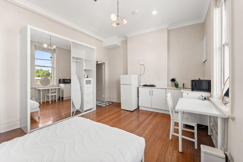 a white room with a bed and a table and a kitchen at Olympic Paddington Budget Hotel - across Allianz Stadium in Sydney