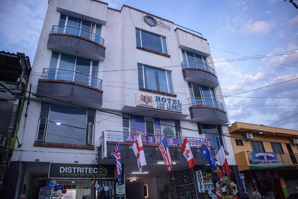a tall white building with flags in front of it at Hotel BENNY Los Leones Melgar in Melgar