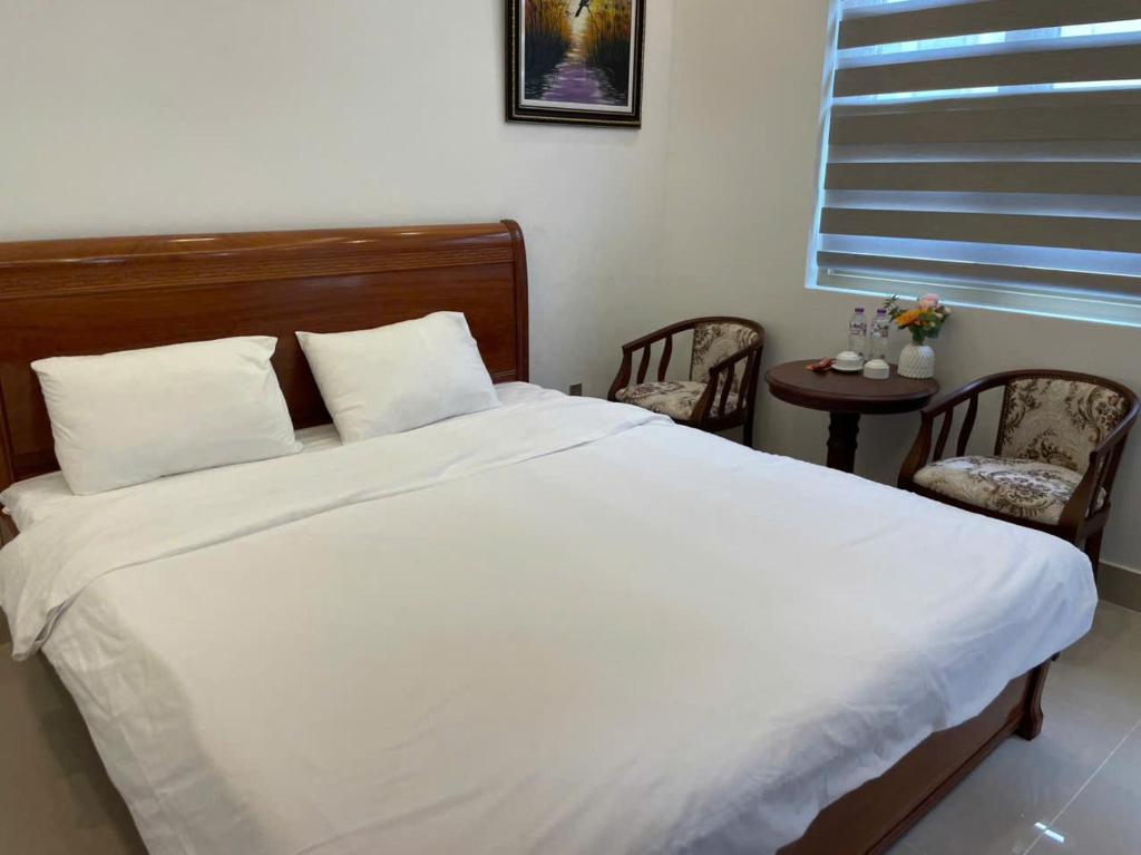 a bedroom with a bed with two chairs and a window at Home Me 1 in Dong Hoi