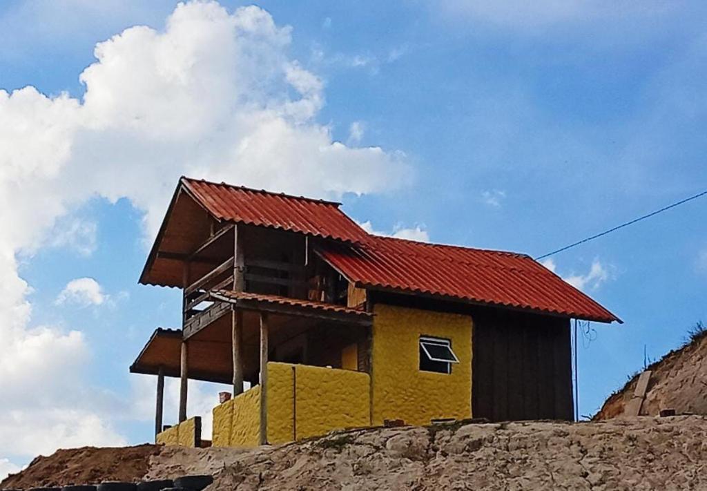 a house with a red roof on top of a hill at Chalé dos ventos in Itamonte