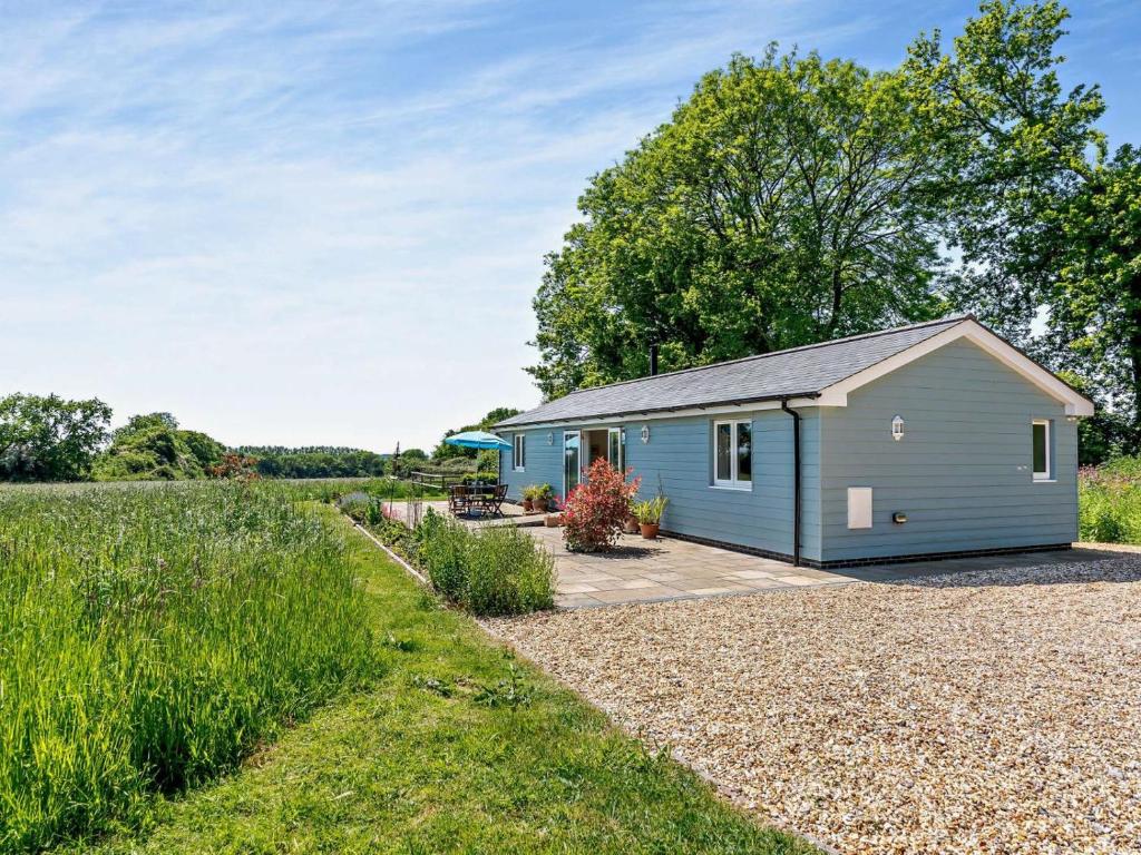 a blue shed with a gravel driveway next to a field at 2 Bed in Winchester oc-77384 in Owslebury