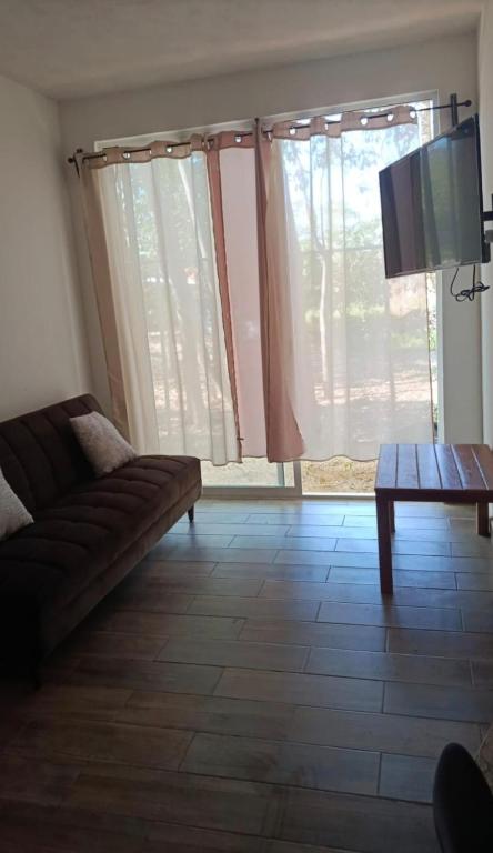 a living room with a couch and a table and a tv at Coastal Charm in Ixtapa