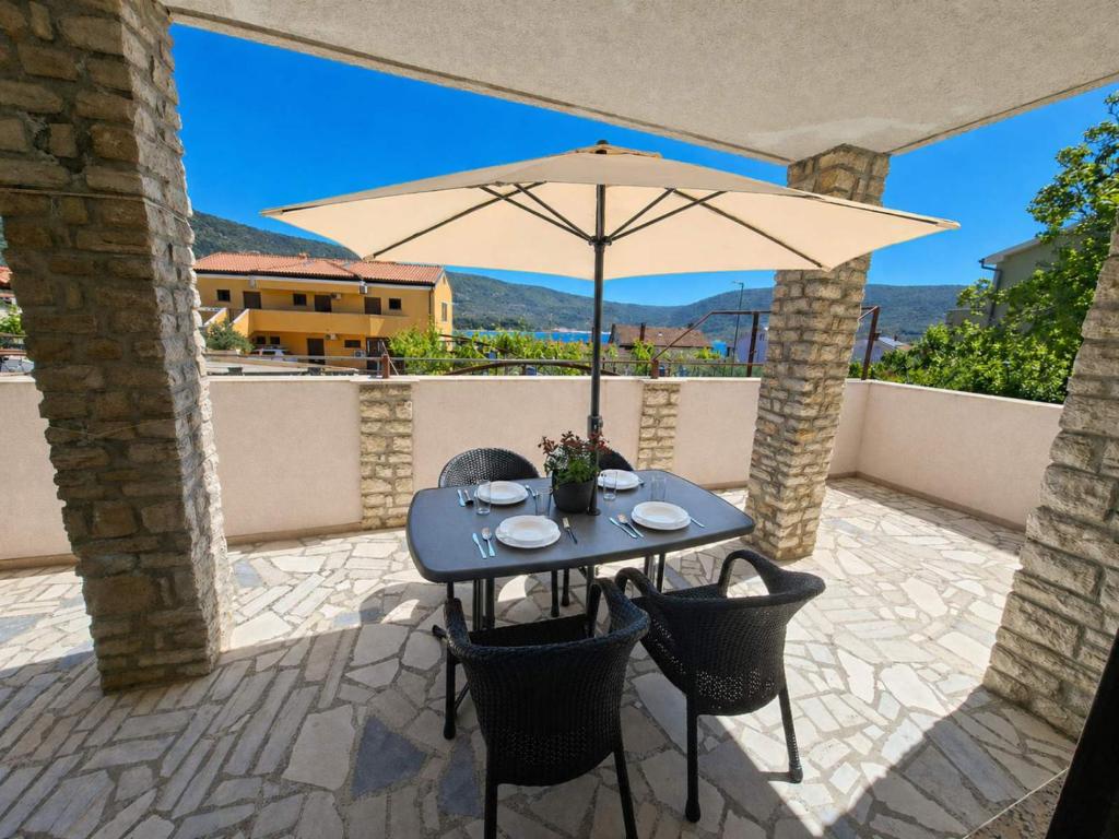 a blue table with an umbrella on a patio at Apartments Renato Mužić Cres in Cres