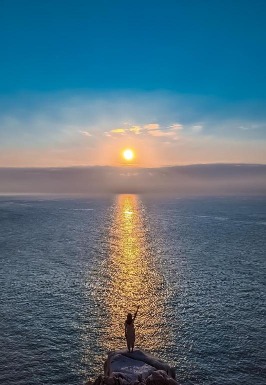 a person standing on a rock in the ocean at sunset at Om Tara Retreat in Yên Bái