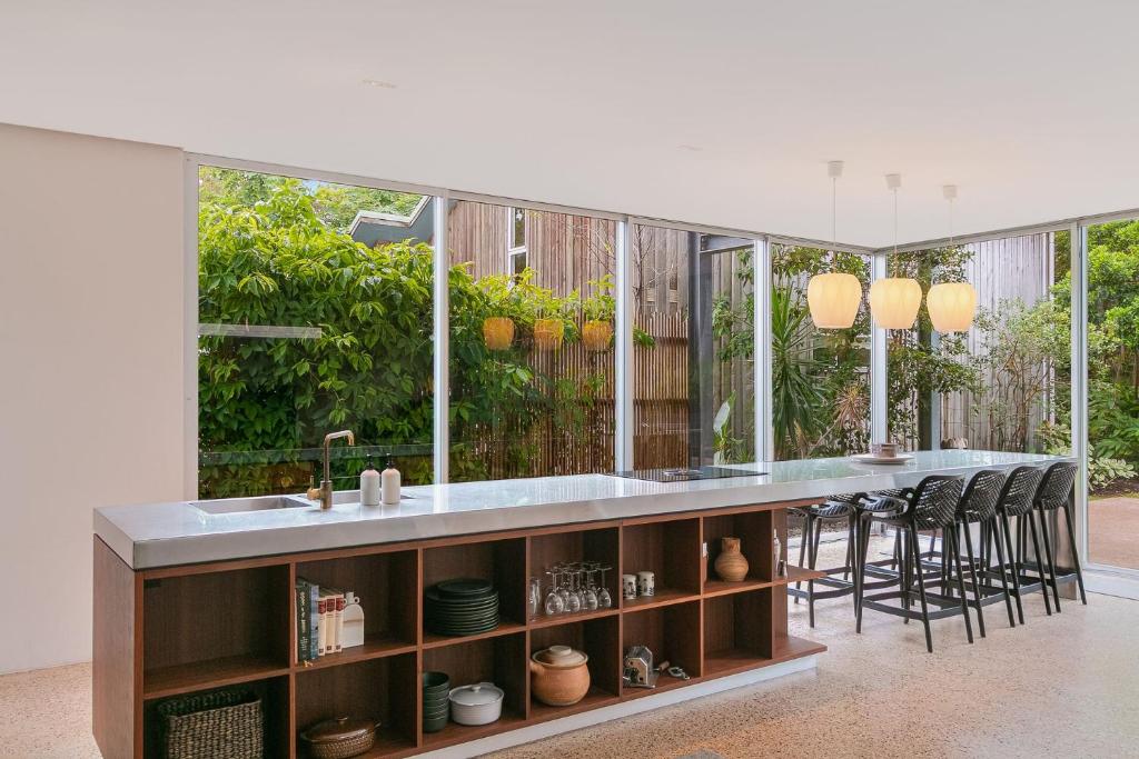 a kitchen with a counter with a sink and stools at Dune Ten in Fingal Head