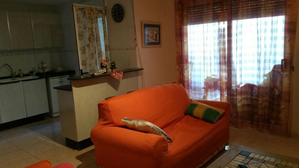 an orange couch in a living room with a kitchen at Apartamento Rosaleda in Denia