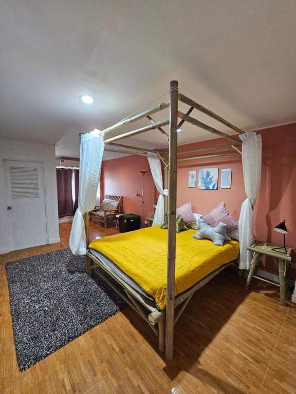 a bedroom with a canopy bed with yellow sheets at Papa house red room in Pak Kret