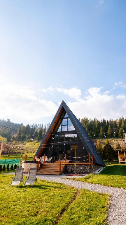 a frame house with two chairs in the grass at Peaceful Cabin in Lunca Bradului