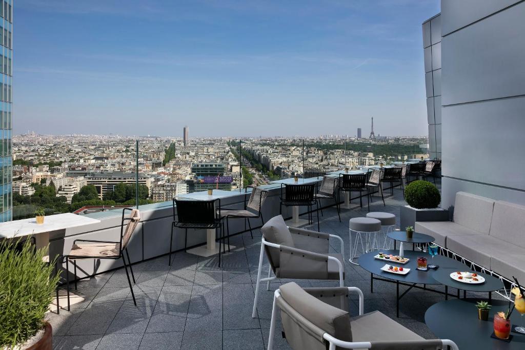 a rooftop patio with tables and chairs on a building at Meliá Paris La Défense in Courbevoie