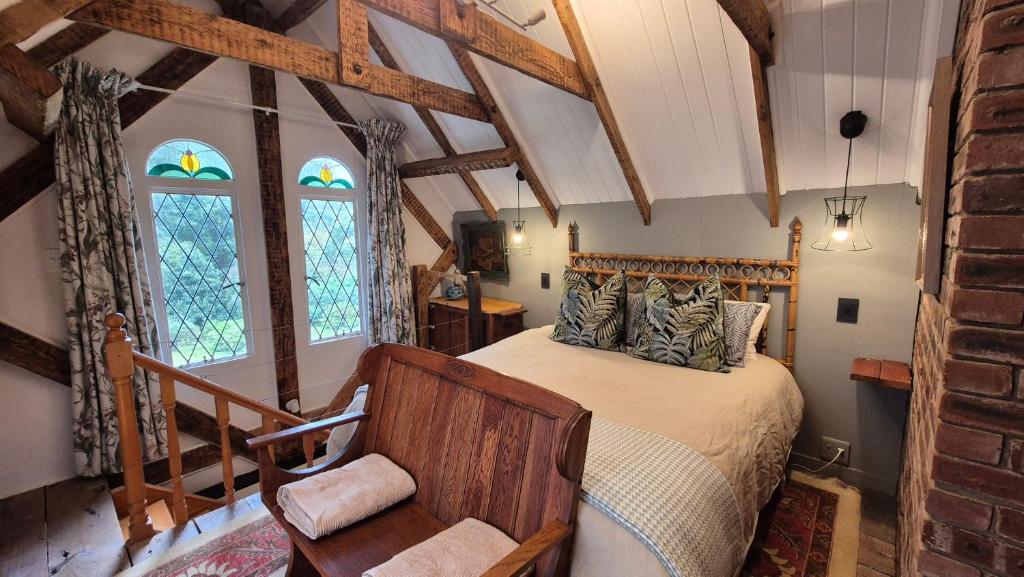 a bedroom with a bed and a chair in a room at Lacebark Cottage in Hilton