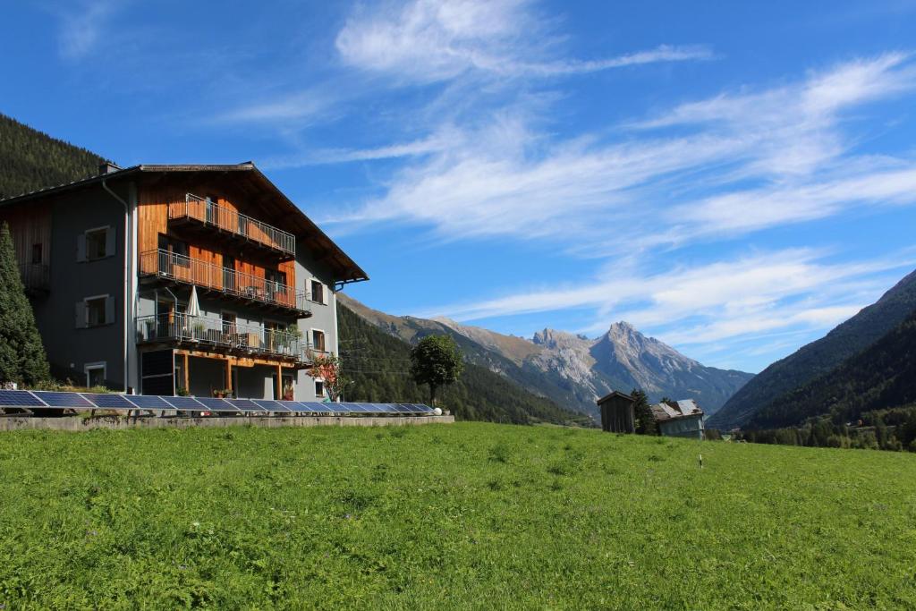 a building in a field with mountains in the background at Gästehaus Kolp in Sankt Anton am Arlberg