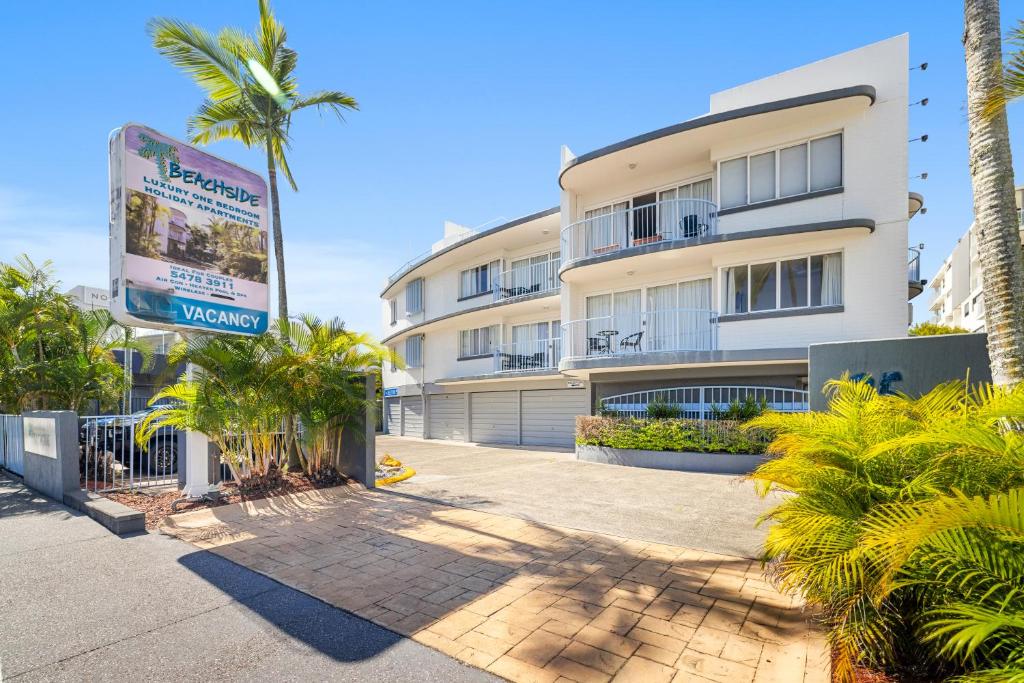 un grand bâtiment avec des palmiers devant dans l'établissement Beachside Mooloolaba, à Mooloolaba