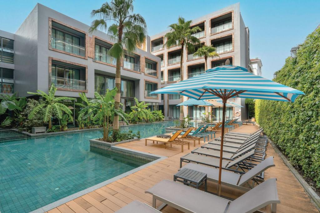 a swimming pool with lounge chairs and an umbrella at Sugar Marina Hotel-SURF-Kata Beach in Kata Beach