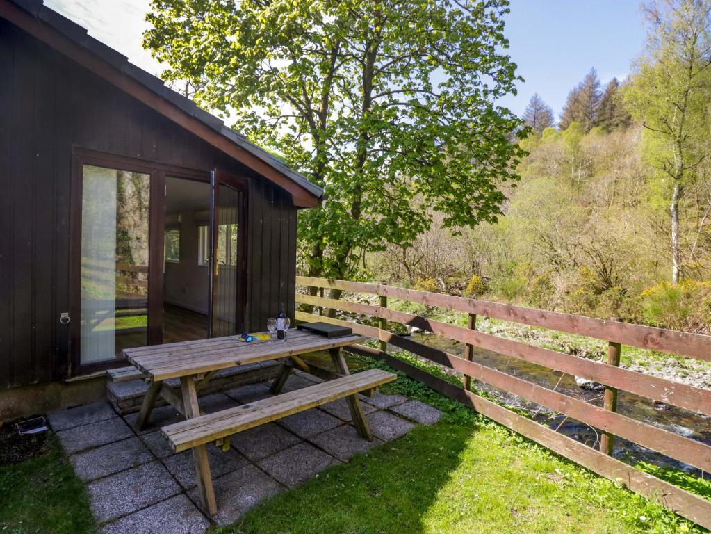 a wooden picnic table on a patio next to a fence at Chestnut Timber Lodge in Keswick