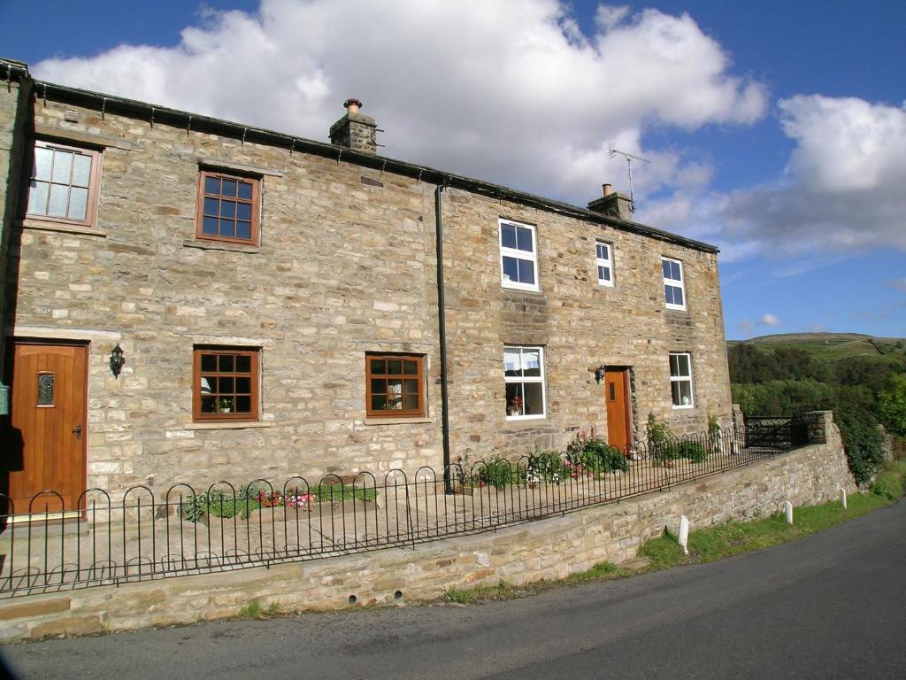 a stone building with a man on top of it at Scarr House Farm in Muker