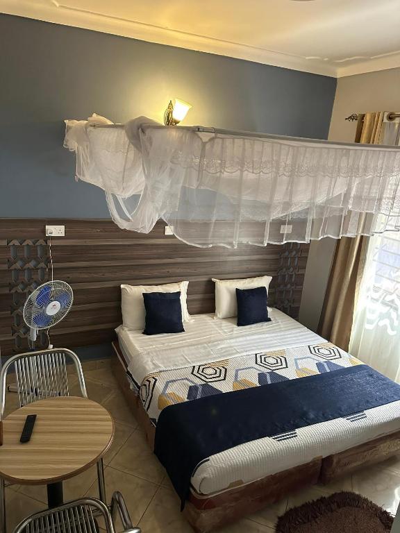 a hotel room with two beds and a table and a bed at Aape Motel Kamuli in Kamuli