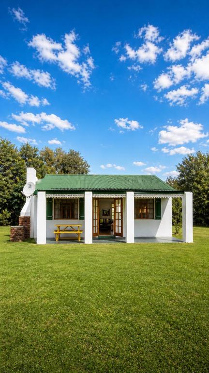 a house with a green roof on a grass field at The Farmers Cottage Bethulie at Karoo Pandok in Bethulie