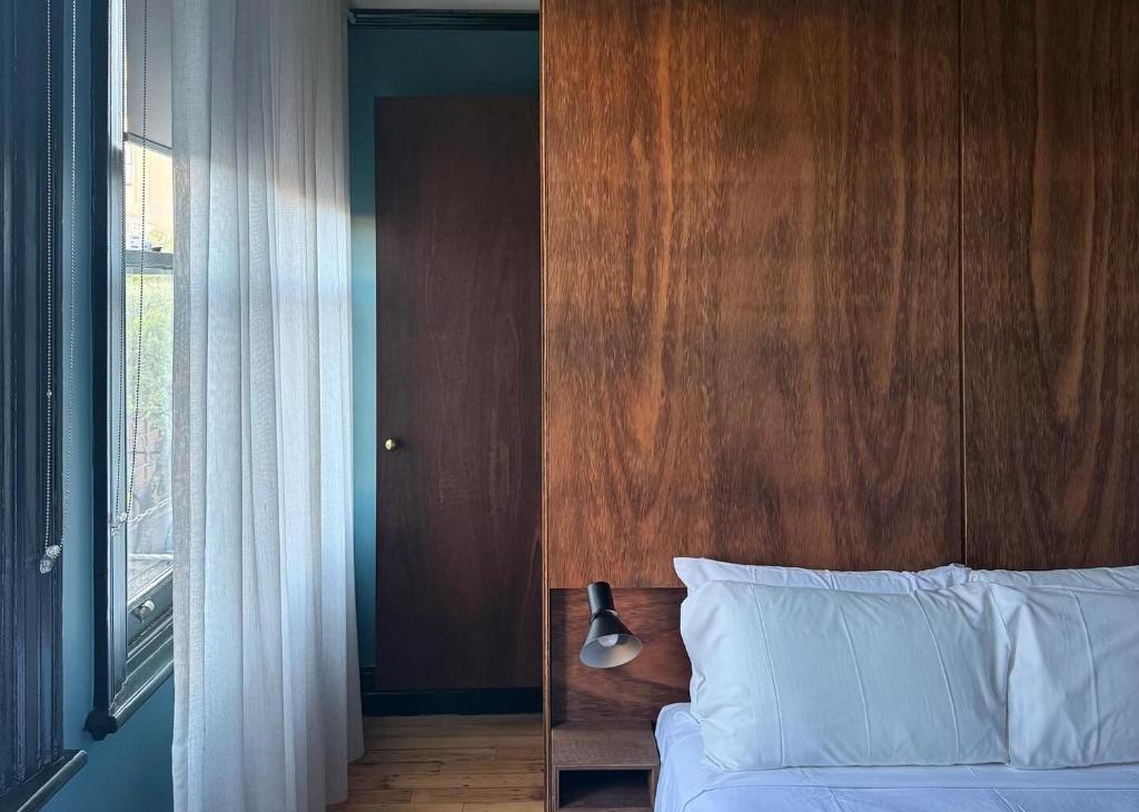 a bedroom with a bed with a wooden headboard and a window at Mercantile Hotel in Sydney