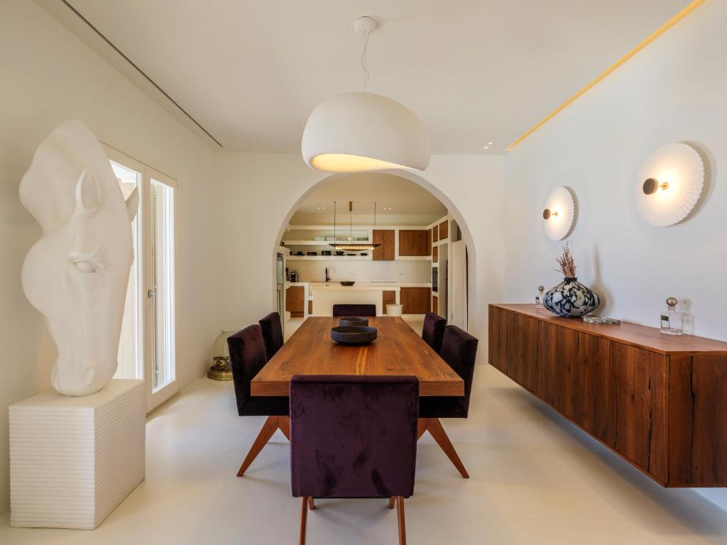 a dining room with a wooden table and chairs at Villa Venti Private Pool Retreat, Mykonos in Agios Ioannis Mykonos