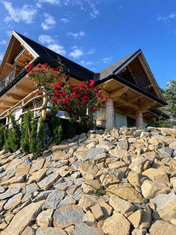 a log home with flowers on a stone wall at Gliniana Chata in Zawoja
