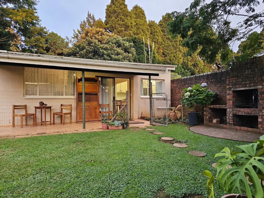 a home with a patio and a yard with a table at Leopards Tree Garden Cottage in Greytown