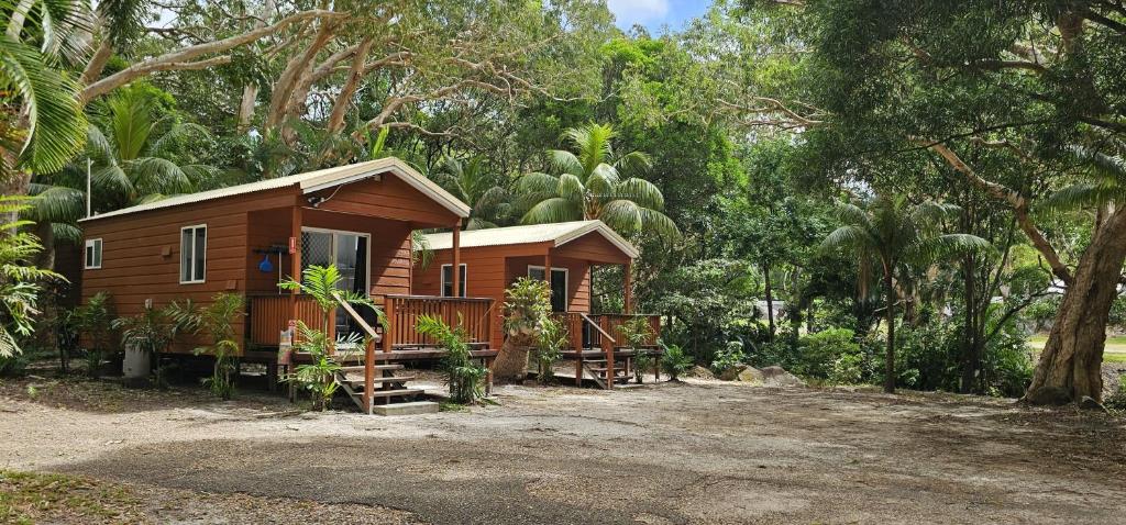 a small wooden house in the middle of trees at Peninsula Caravan Park Cooktown in Cooktown