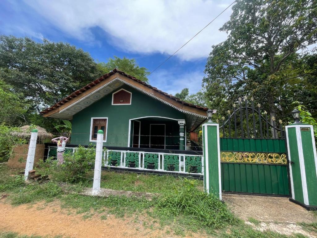 a green house with a fence and a gate at Ceylona Homestay in Kurunegala