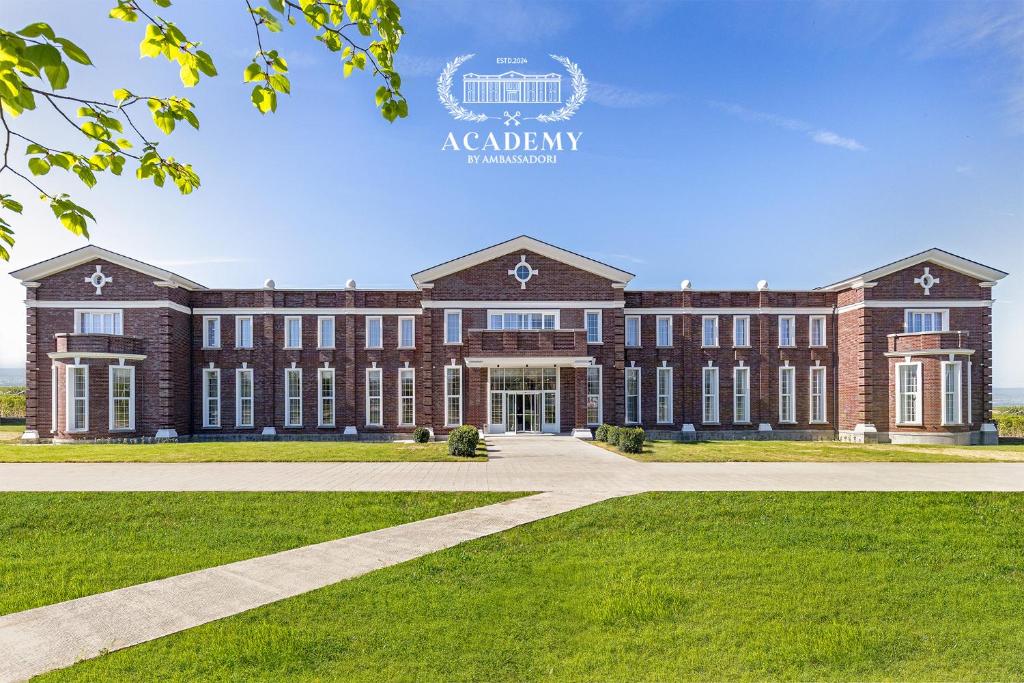a large brick building with a lawn in front of it at Academy by Ambassadori in Kachretʼi