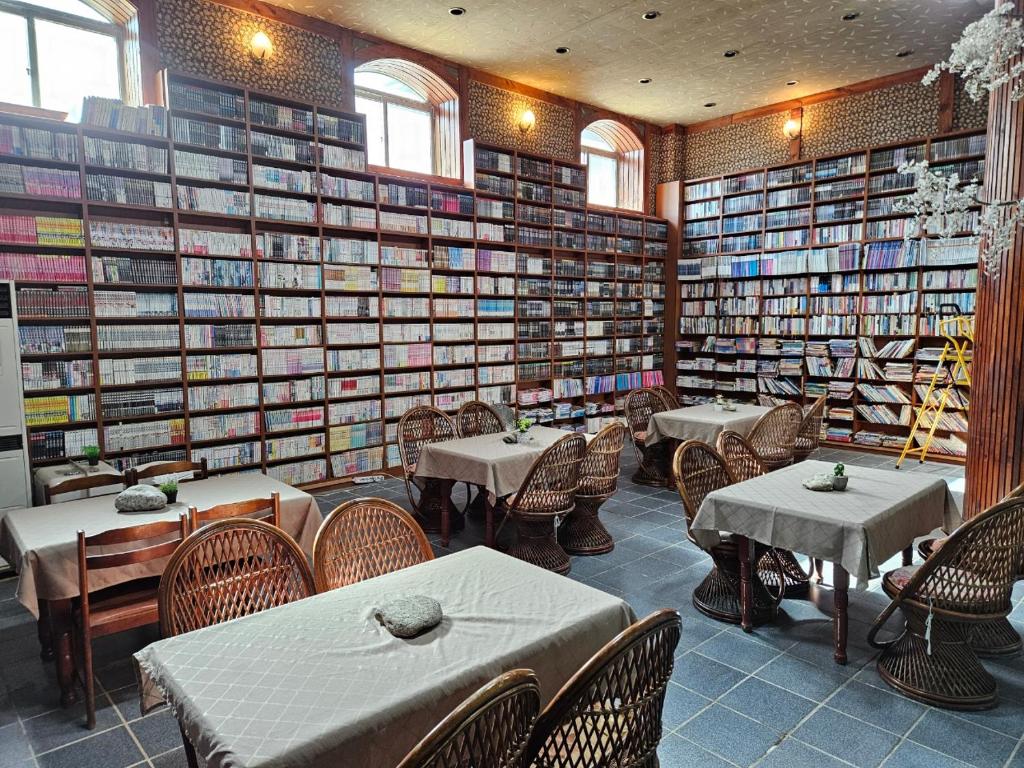 a restaurant with tables and chairs in a room filled with books at Bandal Book & Stay in Sokcho