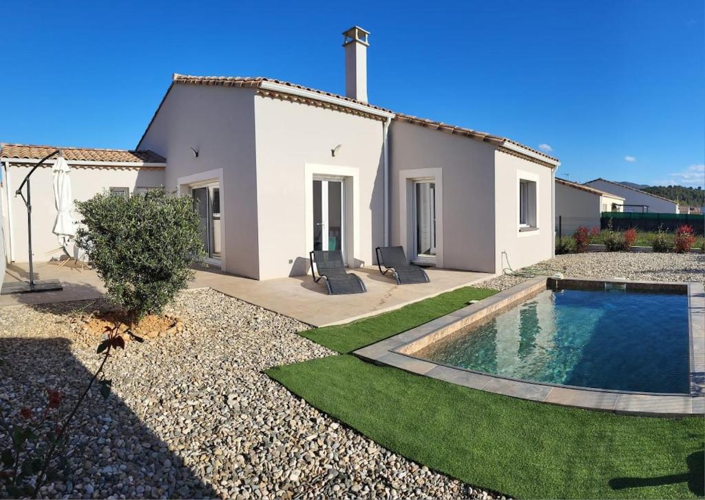 a villa with a swimming pool in front of a house at Maison avec piscine in Cessenon