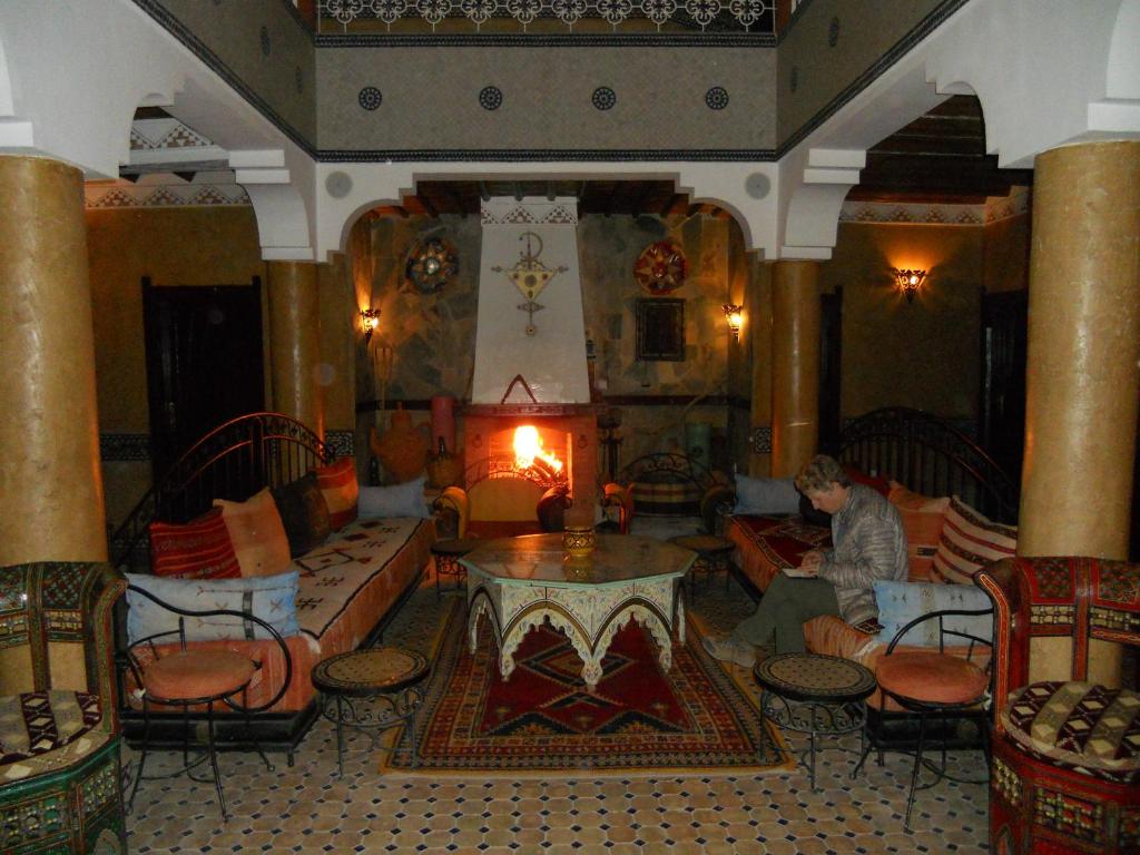 泰夫勞特的住宿－Hotel Salama STE SAL- AMA SUD SARL AU，坐在带壁炉的客厅里的人