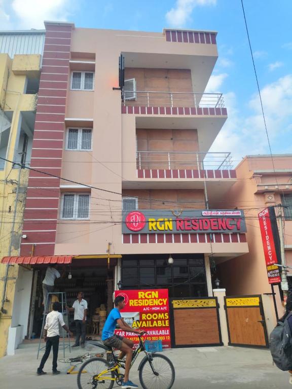 a person riding a bike in front of a building at Rgn Residency in Singānallūr