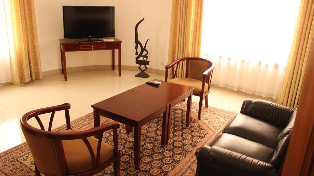 a living room with a table and chairs and a television at Hotel Residence Flamani in Lomé
