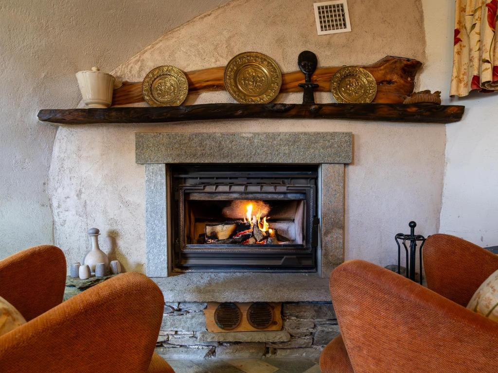 a living room with a fireplace with two chairs at Meira Carlevara in San Maurizio
