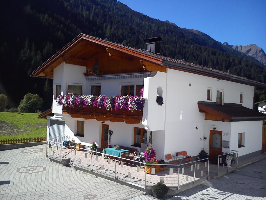 a white house with flowers on the front of it at Apartment Familie Thomas und Angelika Melmer in Sankt Leonhard im Pitztal