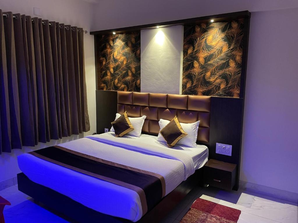 a bedroom with a large bed with a blue light at Hotel Durga International in Udupi