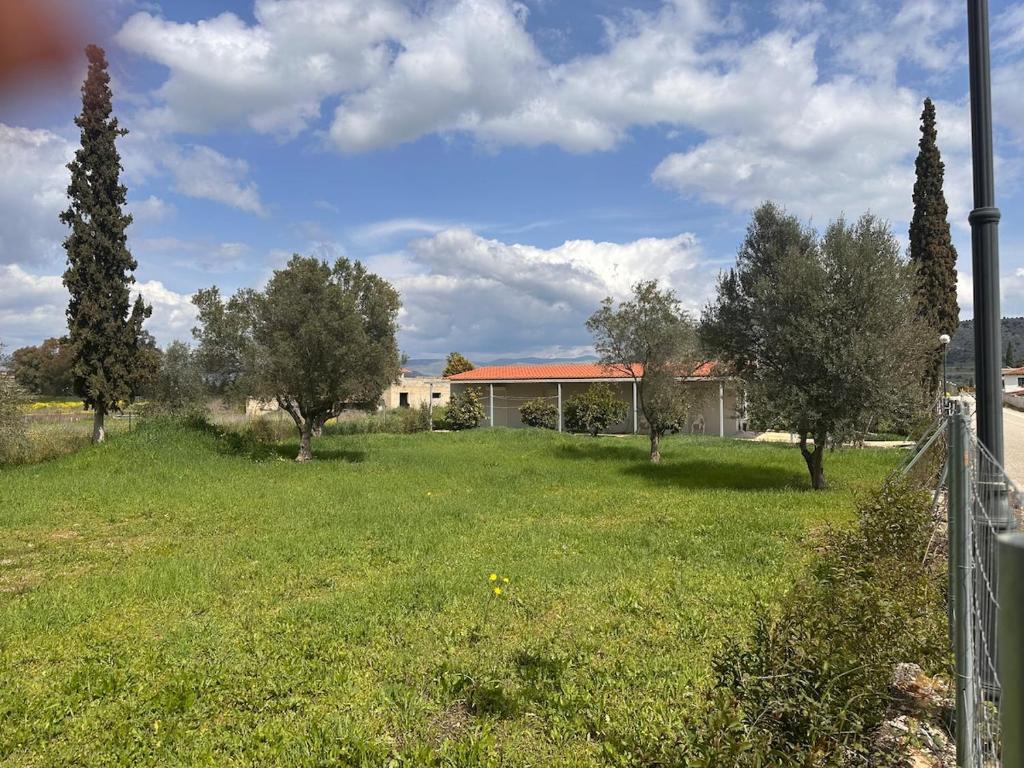 a house with a yard with trees and a fence at Nafplio Garden House in Nea Tiryntha