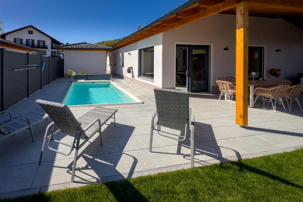 a patio with chairs and a swimming pool at Bayerwald-Bungalow in Grattersdorf