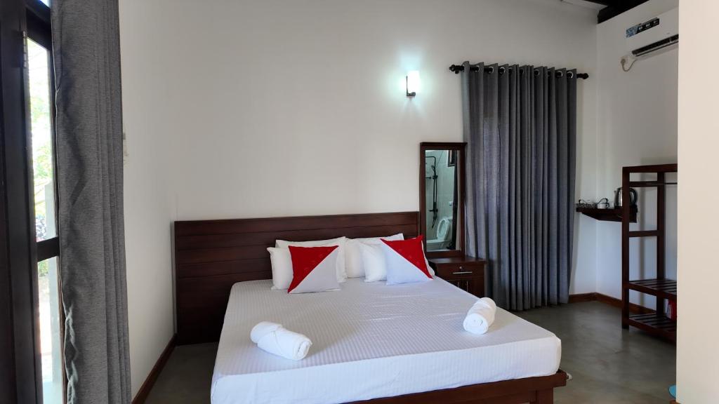 a bedroom with a bed with red and white pillows at wild elephant reach wilpaththuwa in Nochchiyagama