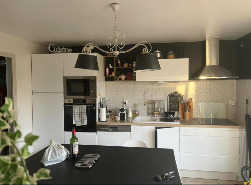 a kitchen with white cabinets and a black counter top at Maison, atypique, proche, mer in Plérin