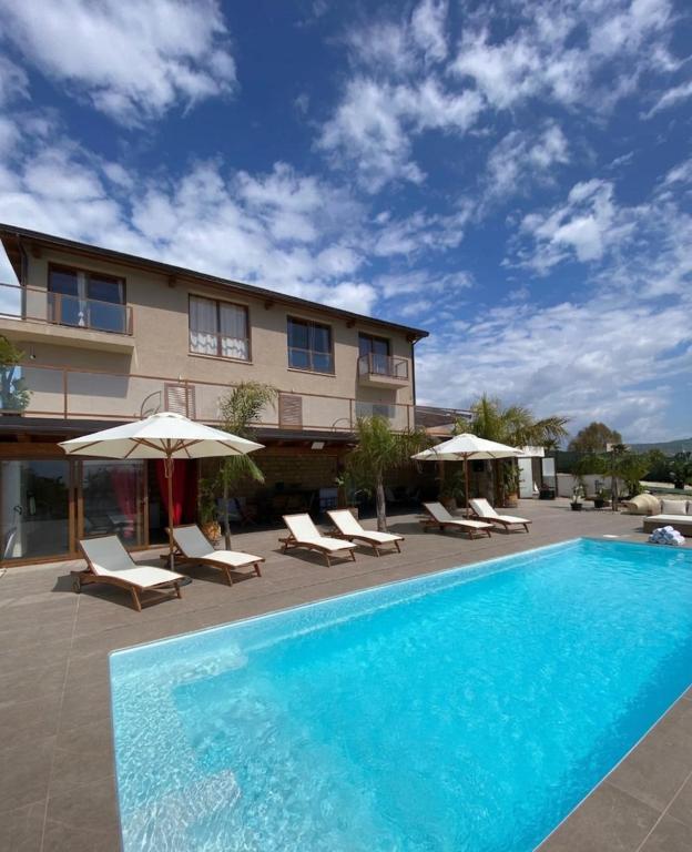 a swimming pool with chairs and umbrellas next to a building at Le tenute di punta bianca in Agrigento