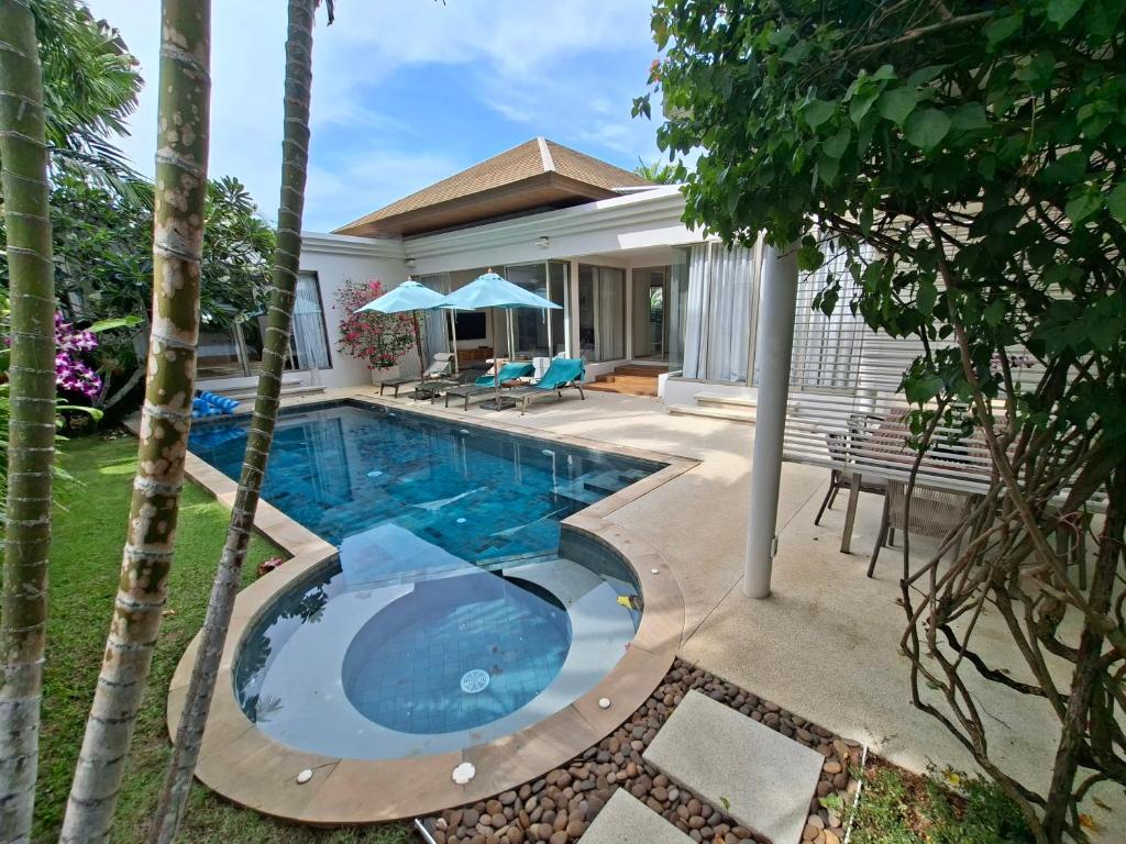 a swimming pool in front of a house at Villa Desi in Bang Tao Beach