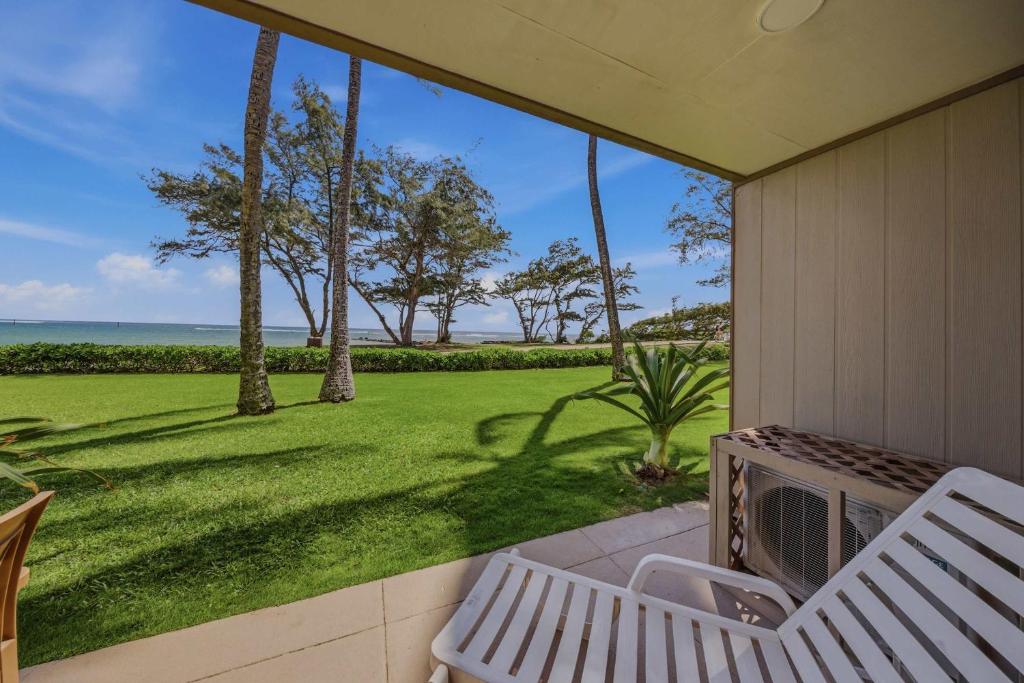 a porch with a bench and a view of the ocean at Oceanfront Escape Pono Kai Resort A103 in Kapaa