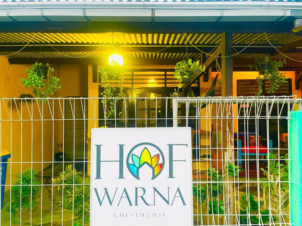a sign on a fence in front of a building at Hof Warna Guesthouse in Yogyakarta