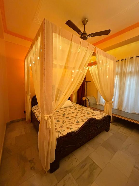 a bedroom with a canopy bed with a ceiling fan at H&R Homestay in Guwahati