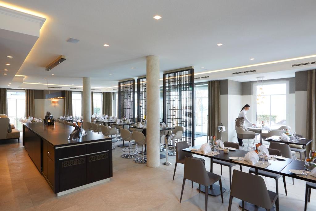 a restaurant with tables and chairs and a man in the background at Strandhotel Fontana in Timmendorfer Strand